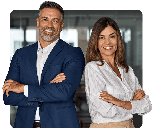 A man and a woman, exuding confidence, stand with arms crossed in an office. He sports a blue suit while she dons a white blouse and beige pants. The blurred office elements suggest a setting for therapy in Fort Bend County, TX.